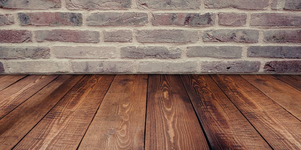 A floor of engineered luxury vinyl installed against a real stone wall.