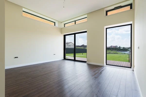 A room with windows having vinyl plank flooring with stone core.