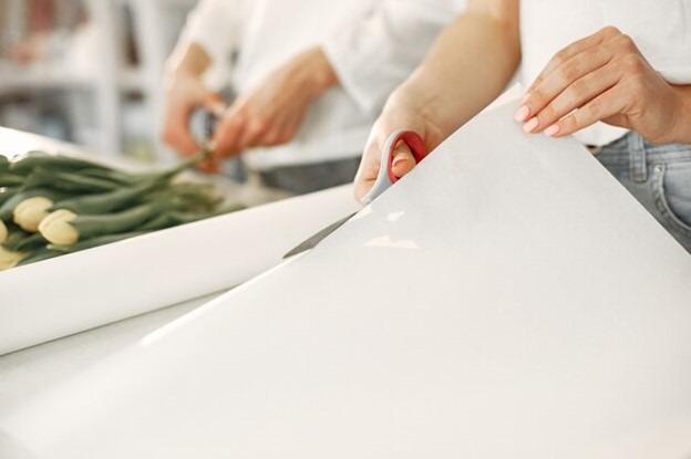 A man cutting a vinyl paper for installation.