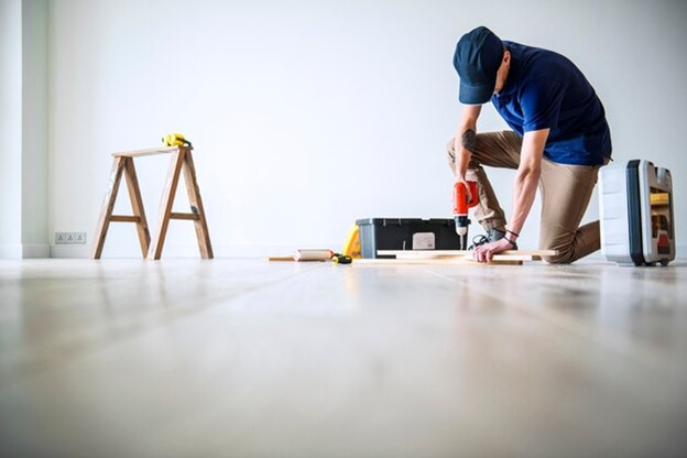 A DIYer installing glue-down LVP on the floor.